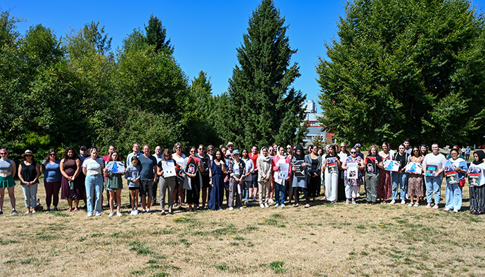 Group photo of several dozen people, many holding signs in support of the women of Afghanistan. They are lined up to pose for a photo.
