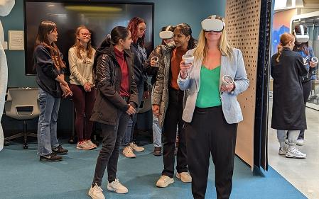 A person wearing virtual reality goggles in a room full of people.